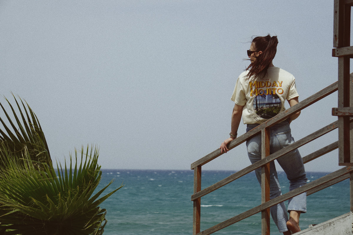 Frau trägt Midday Mojito T-Shirt mit Strand-Print am Meer